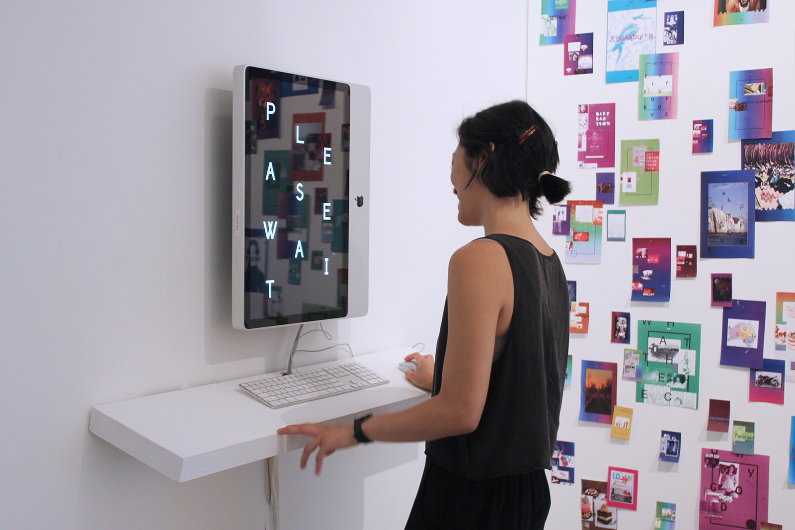 A young Asian woman laughing while facing the 'PLEASE WAIT' screen. The letters are arrayed diagonally across the screen.